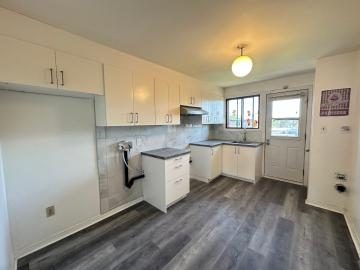 Cuisine repeinte en blanc avec plancher de bois pâle et fenêtre au-dessus de l'évier